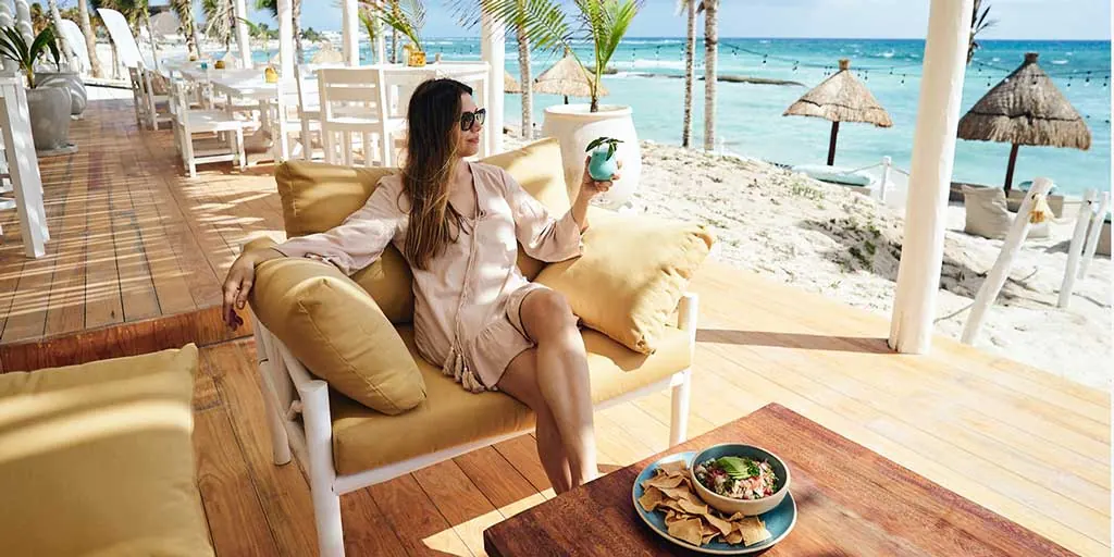 Lounge deck on the sand with palapa umbrellas at KAY Beach Club, the Country Club’s own beach club