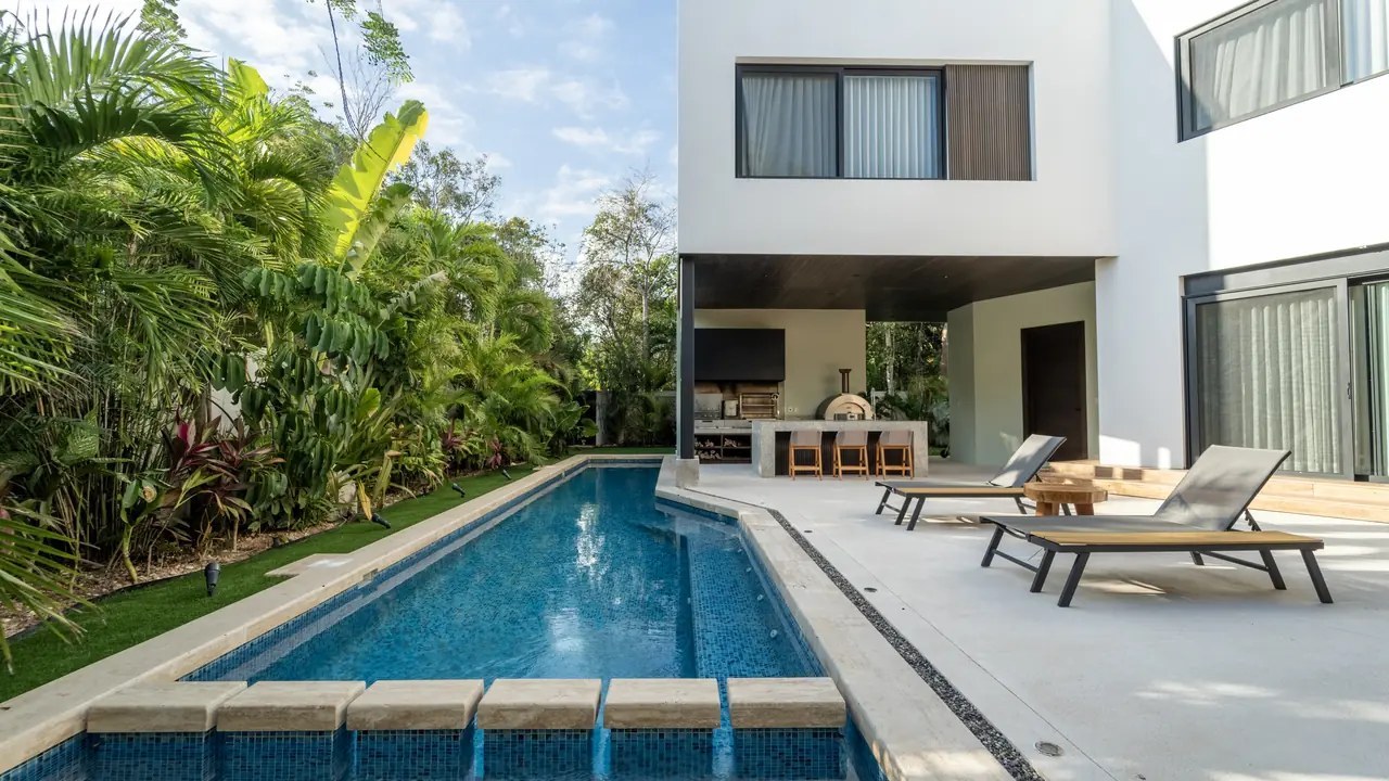 Long private pool and terrace of a villa surrounded by tropical garden